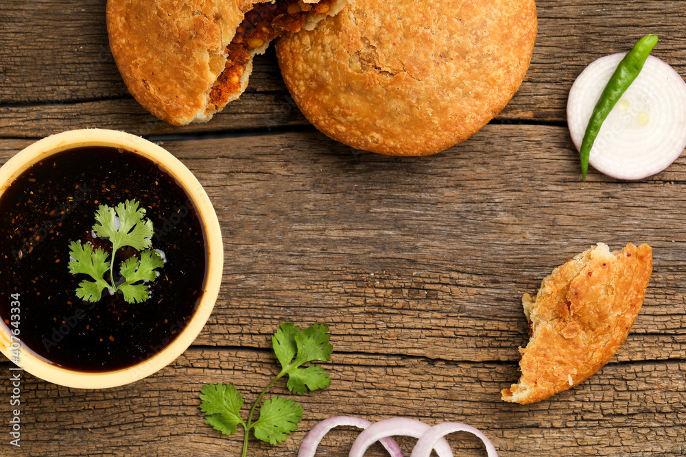 Kachori, green chilly and onion slice on wooden background. kachori is a spicy snack from India also spelled as kachauri and kachodi.