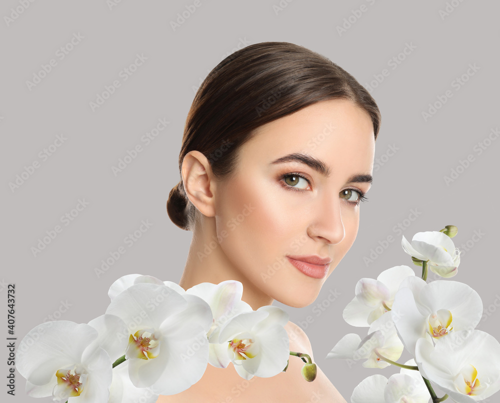 Beautiful young woman and orchid flowers on light background. Spa portrait Beautiful young woman and orchid flowers on light background. Spa portrait