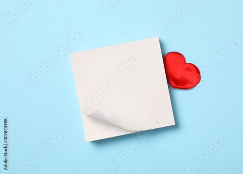 Blank notes and decorative heart on light blue background, flat lay with space for text. Valentine's Day celebration