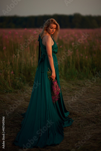 Young beautiful girl with a bouquet of flowers in her hands at sunset.