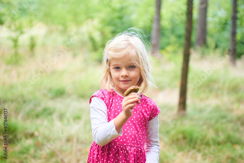 Child girl in the forest and holding an edible mushroom