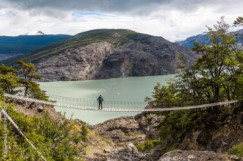 Male tourist looking at Grey Lake while staying on suspension bridge, Torres del Paine National Park (CL)