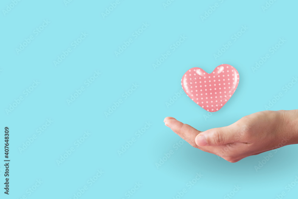 Close up of woman hands with heart with clean pastel background. Valentine's Day Love and care.
