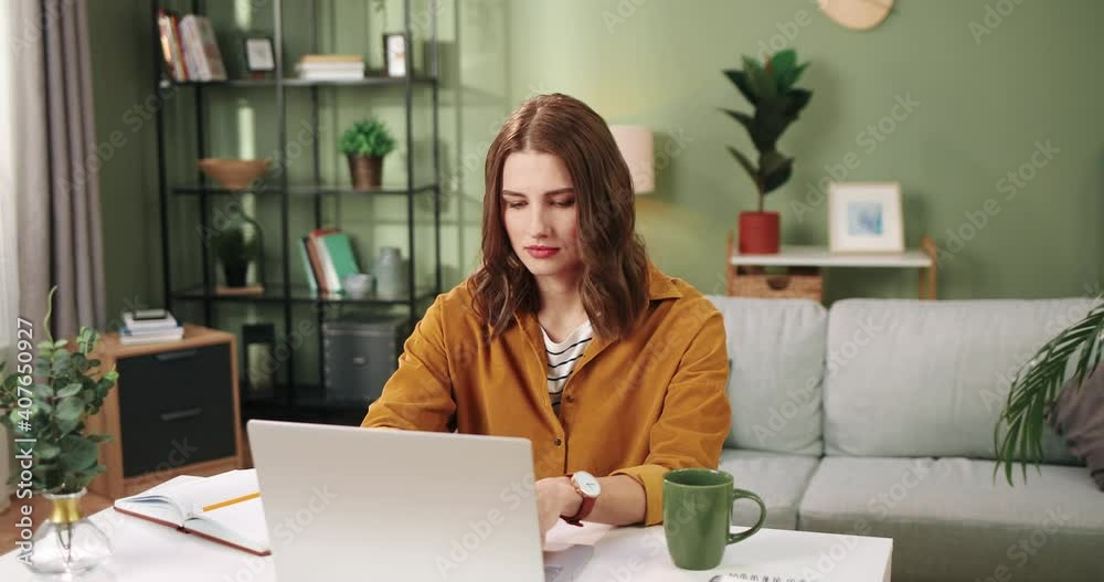Camera approaching young beautiful Caucasian happy woman typing and surfing internet on laptop working on computer and smiling while sitting in cozy room alone. distance learning, Portrait concept Camera approaching young beautiful Caucasian happy woman typing and surfing internet on laptop working on computer and smiling while sitting in cozy room alone. distance learning, Portrait concept