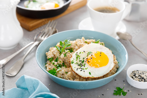 Fotografija Savoury oatmeal with fried eggs sunny side up for breakfast