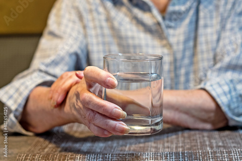 old women's hands holding a glass of water
