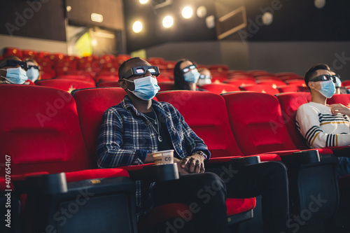People sit in the cinema hall and watch a movie wearing medical masks and keep their distance. Covid-19 and the film industry © xartproduction