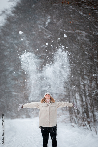 Winter playing woman throwing up snow in the park
