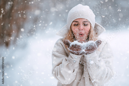 Winter woman blow snow while walk in the park
