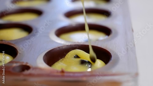 pouring the filling into the form of chocolates from a pastry bag
