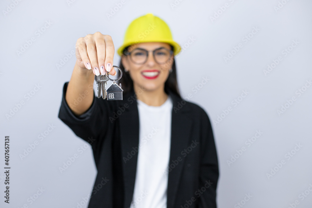 Young architect woman wearing hardhat holding the key of a new house. Real state concept Young architect woman wearing hardhat holding the key of a new house. Real state concept