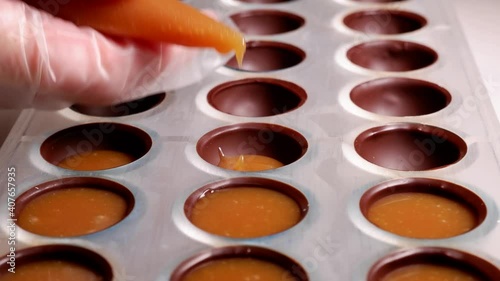 pouring the filling into the form of chocolates from a pastry bag