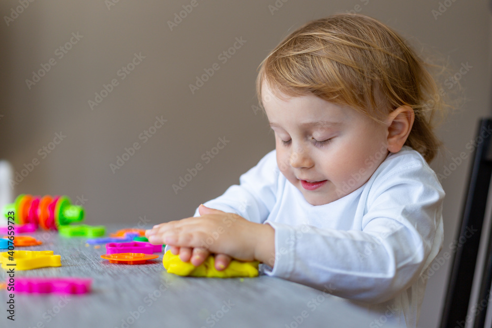 Cute little boy moulds from colored plasticine on table. Home schooling. Creative leisure with children during corona virus quarantine staying at home. Cute little boy moulds from colored plasticine on table. Home schooling. Creative leisure with children during corona virus quarantine staying at home.