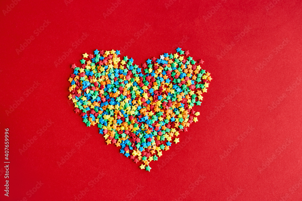 Fototapeta premium Heart made of multi-colored stars on red backgroud. Colorful valentines day