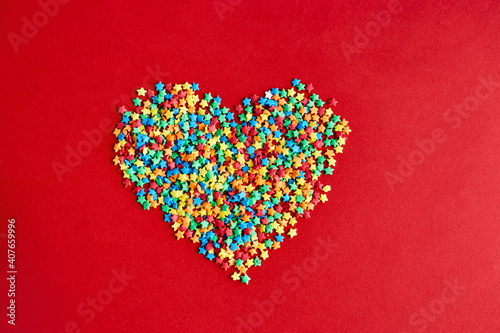Heart made of multi-colored stars on red backgroud. Colorful valentines day
