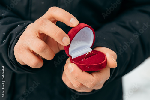 The guy holds in his hands a box with a ring for a marriage proposal