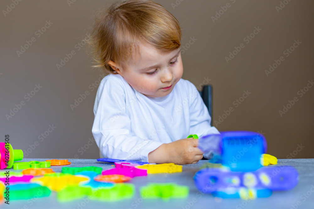 Little caucasian child playing with colorful play dough lying on the table. Early school education. Little caucasian child playing with colorful play dough lying on the table. Early school education.