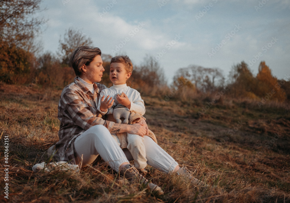 Cheerful pregnant mother spending time with her toddler son in autumnal park. Mother and son. Family having fun outdoors Cheerful pregnant mother spending time with her toddler son in autumnal park. Mother and son. Family having fun outdoors