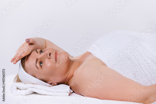 Relaxed senior woman in salon after spa body and facial treatments. White background with space.