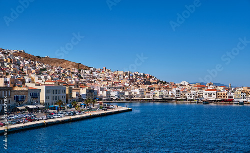 Port of Ermoupoli on Syros island, Greece and harbor. Colorful houses, churches, promenade in summer sun. Island hopping, exploring Mediterranean sea.