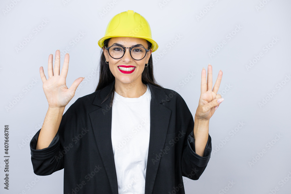 Young architect woman wearing hardhat showing and pointing up with fingers number eight while smiling confident and happy Young architect woman wearing hardhat showing and pointing up with fingers number eight while smiling confident and happy
