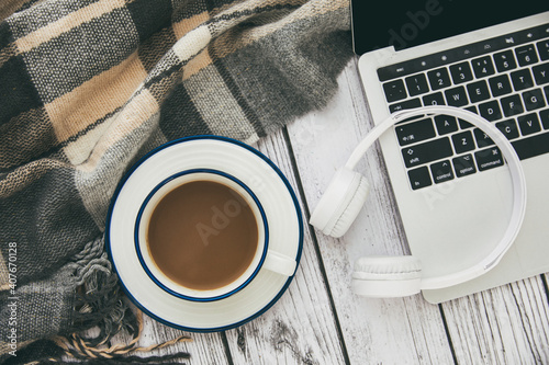 Top view of amodern laptop with white wireless headphones and a cup of coffee on the table photo