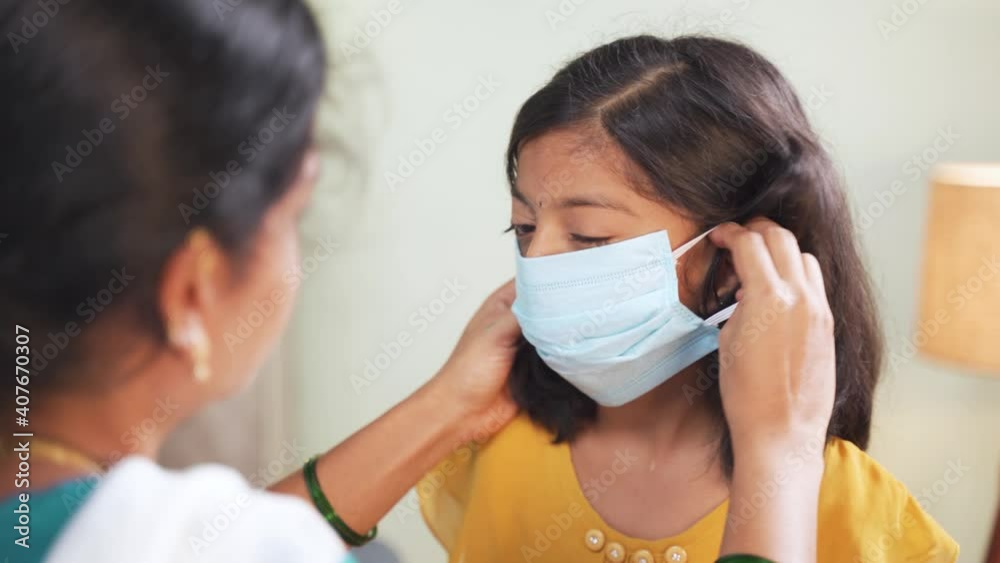 Mother helping her daughter to wear face mask before going to school at home as coronavirus covid-19 healthcare safety measures - concept of back to school Mother helping her daughter to wear face mask before going to school at home as coronavirus covid-19 healthcare safety measures - concept of back to school