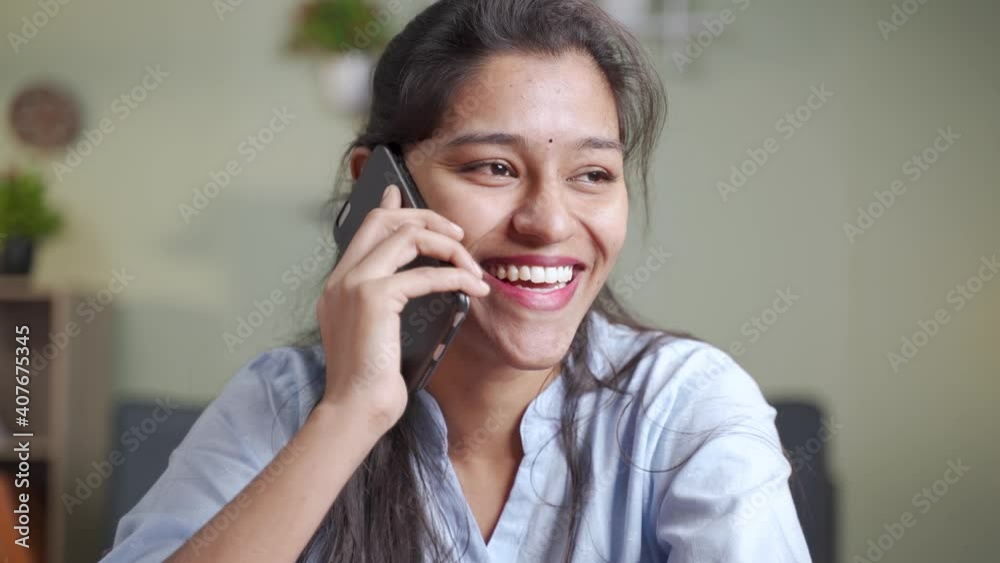 Close up head shot of happy Smiling young Indian business woman busy talking or having conversation on mobile phone call - concept of positive mood or emotion or doing doing time pass at work place Close up head shot of happy Smiling young Indian business woman busy talking or having conversation on mobile phone call - concept of positive mood or emotion or doing doing time pass at work place