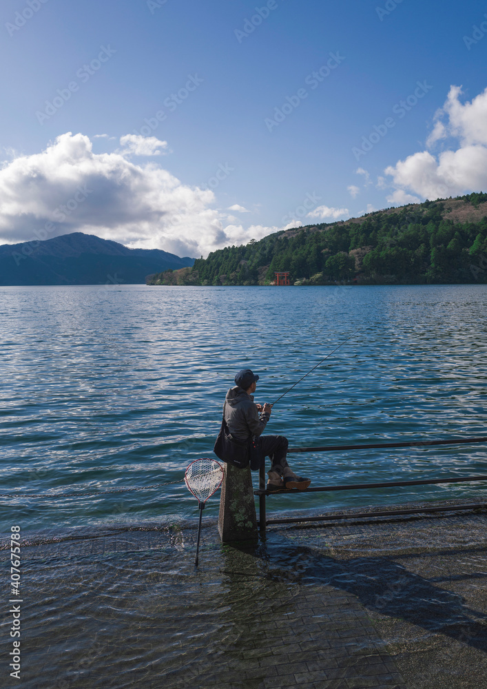 Young man fishing in Lake Ashi, Hakone, Japan.