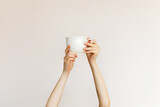 Woman holding a white cup of coffee on clean white wall background.