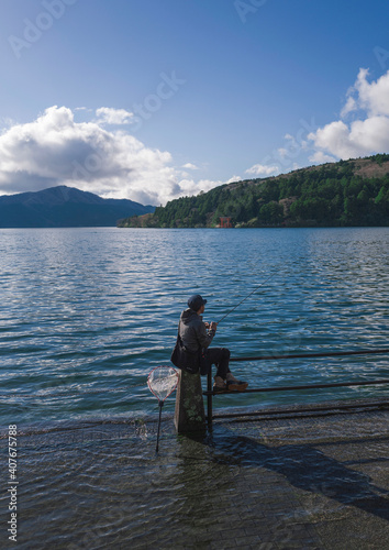 Young man fishing in Lake Ashi, Hakone, Japan.