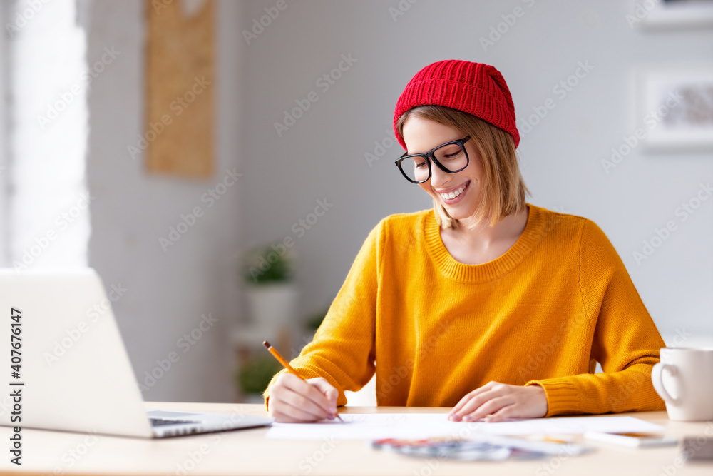 Happy young woman sketching during work Happy young woman sketching during work