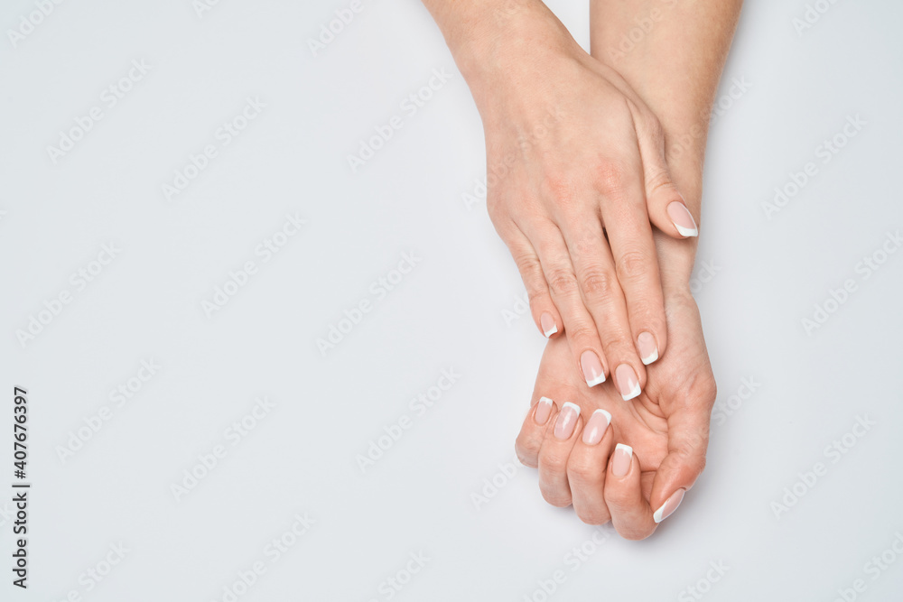 Beautiful Female Hands with French manicure over light grey background Beautiful Female Hands with French manicure over light grey background