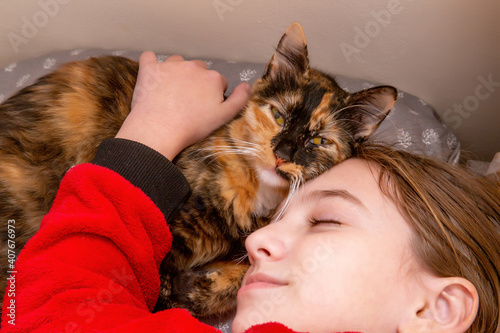 teenage girl in red pajamas sleeping on a pillow with a domestic cat