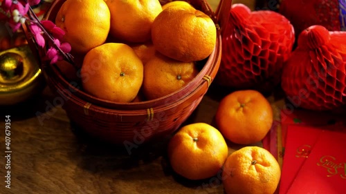 Basket of mandarin oranges and  Chinese new year festival decorations ,red packet,plum blossom ,ingot and lantern on red background.