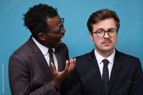 Angry mature businessman scolding his young employee for mistake, Studio shot.