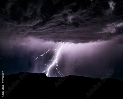 Powerful lightning storm in the American Southwest. One sees the silhouette of the hills on bottom, the lightning, and the cumulonimbus clouds.  photo