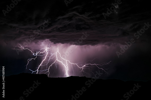 Powerful lightning storm in the American Southwest. One sees the silhouette of the hills on bottom, the lightning, and the cumulonimbus clouds.
