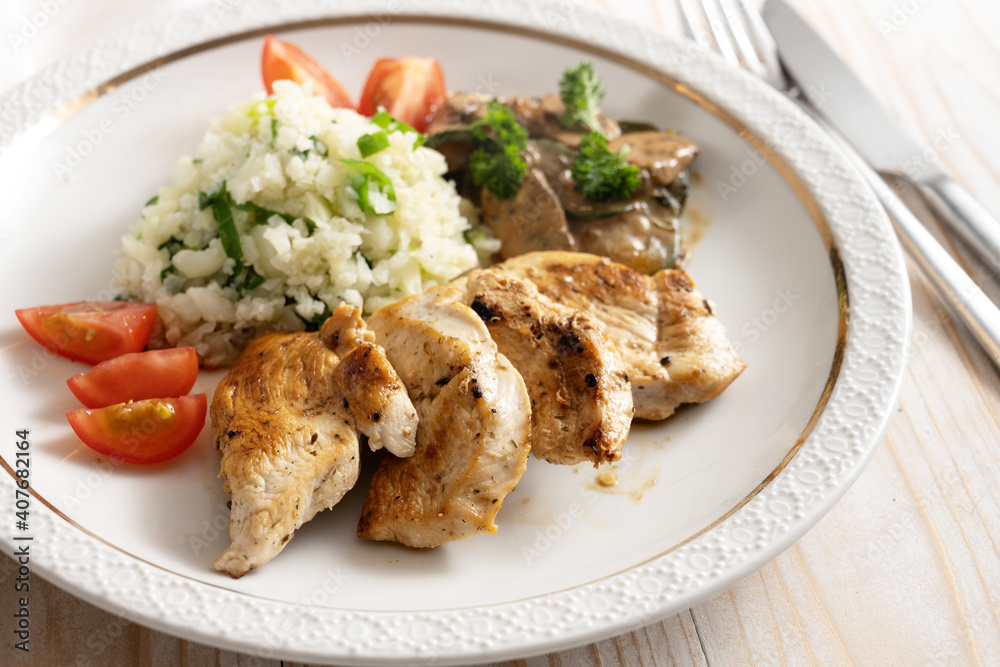 Fried chicken filet with cauliflower rice, tomatoes and mushroom ragout, healthy meal to lose weight with low carb diet