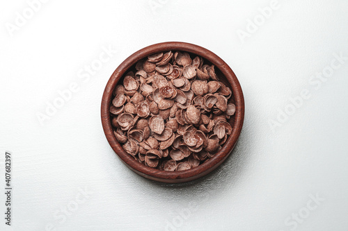 Wooden bowl with chocolate quick breakfast cereal on white background