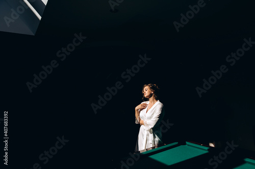 Morning of the bride. Portrait of a girl. The girl in front of the window. Black background.