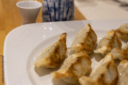 Pan-seared gyozas and bottle of sake from traditional Japanese restaurant (Tokyo, Japan) photo