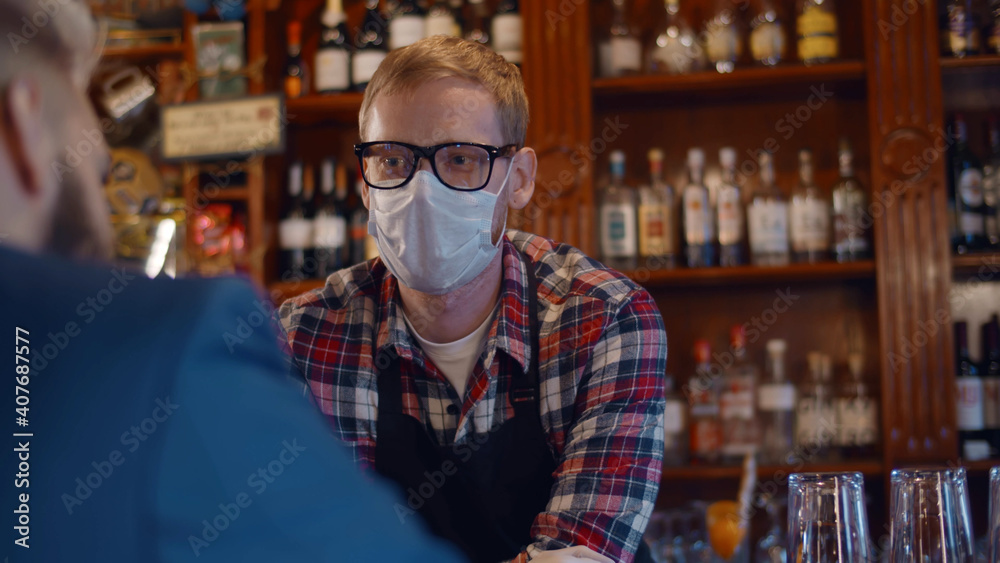 Back view of man client talking to bartender wearing safety mask and gloves