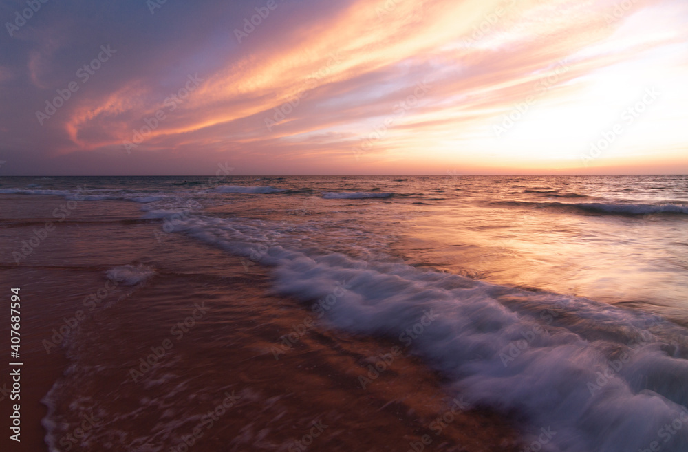 Sunset over the sea shore, sandy beach, colorful sky