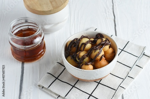 Loukoumades, luqaimat or lokma in white plate on wooden white background. Loukoumades is eastern cuisine donuts popular during Ramazan. Popular Ramadan Food. Iftar and Suhur sweets. Copy space photo