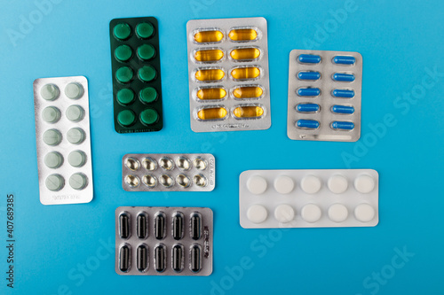 Pharmaceutical medication and medicine pills in packs on blue table