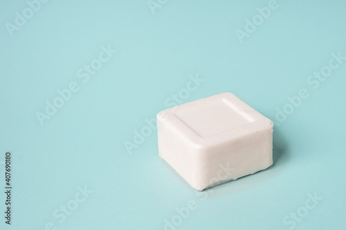 White bar of soap lying on a blue background, minimalistic concept