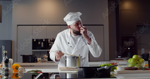 Professional chef tasting sauce and showing sign for delicious. photo