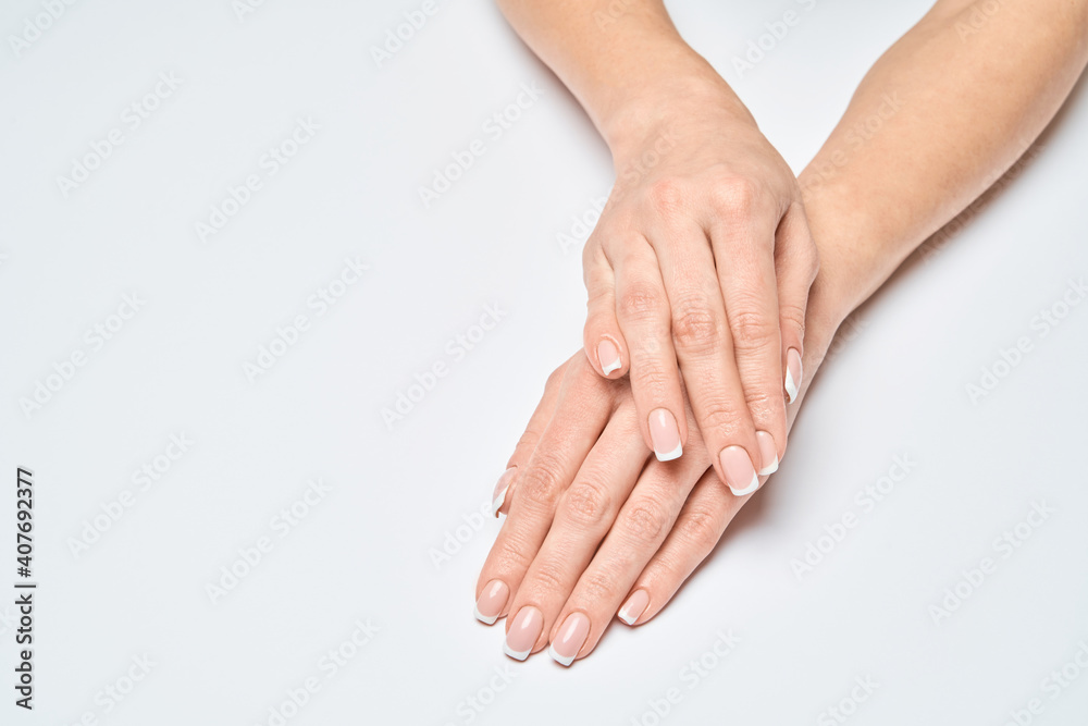 Beautiful Female Hands with French manicure over light grey background Beautiful Female Hands with French manicure over light grey background