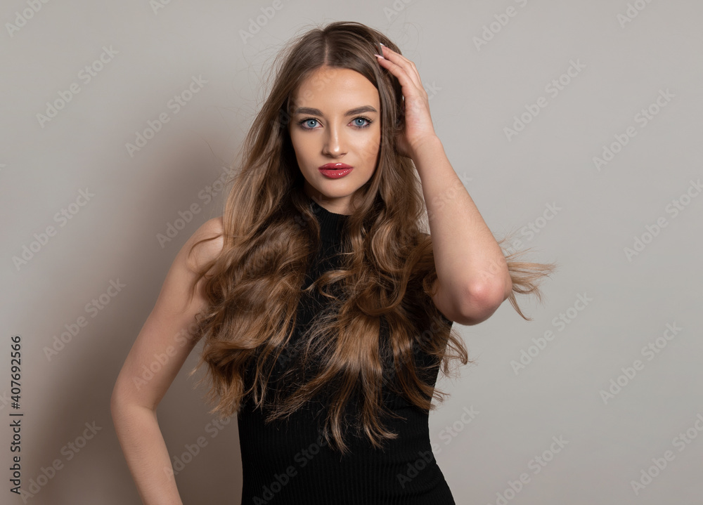 Beautiful young woman with long and healthy wavy hair posing in dress showing healthy figure and wearing wrist watch